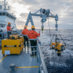 firefly ocean research vessel with scientists deploying underwater drones in open sea, scient 241454